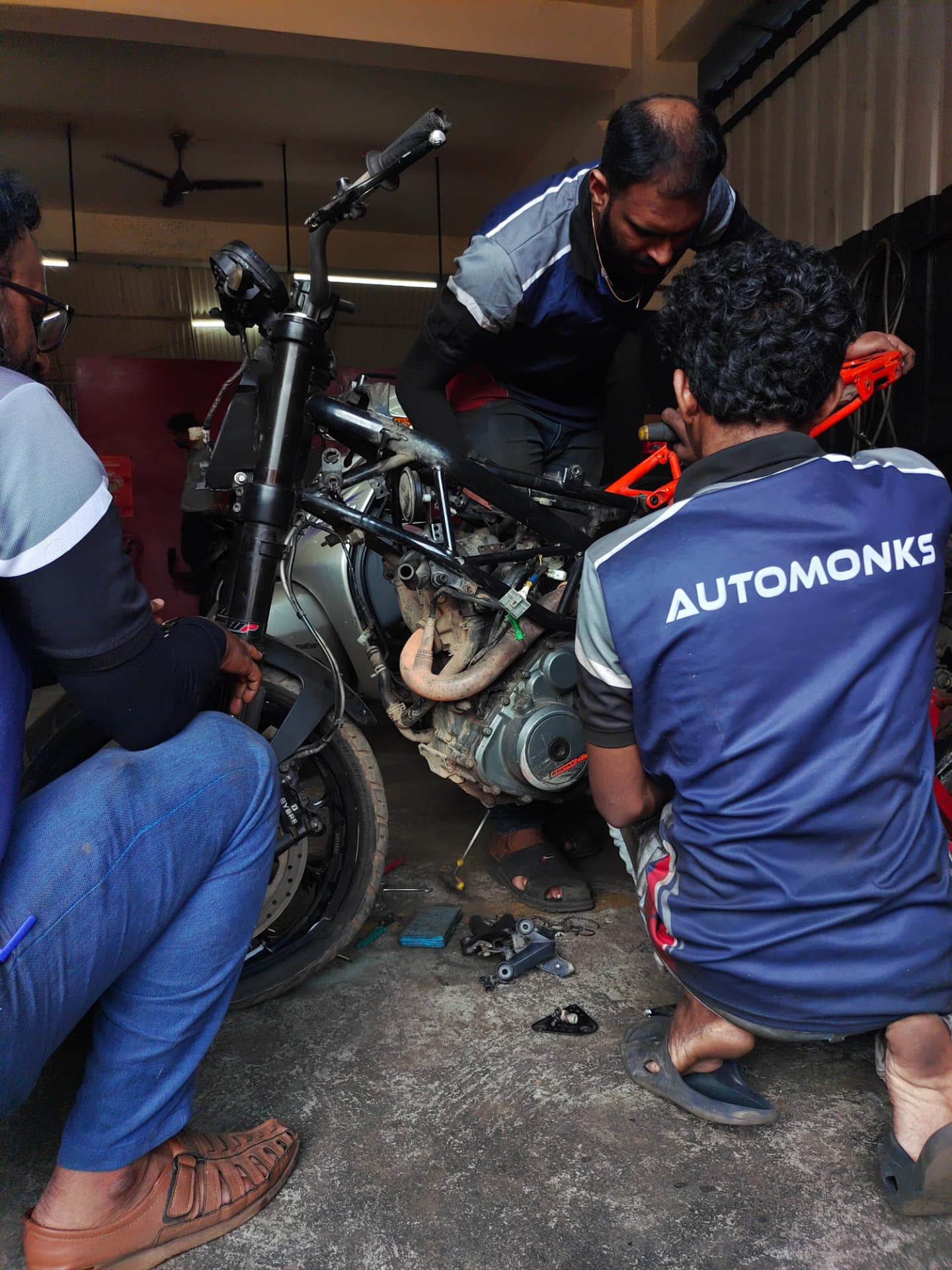 AUTO MONKS technicians working together on a stripped motorcycle